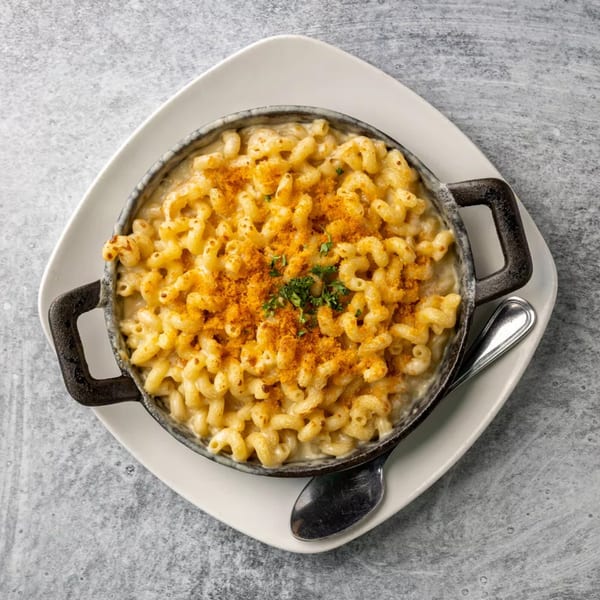 Creamy macaroni and cheese in a black cast iron dish, topped with breadcrumbs and parsley.